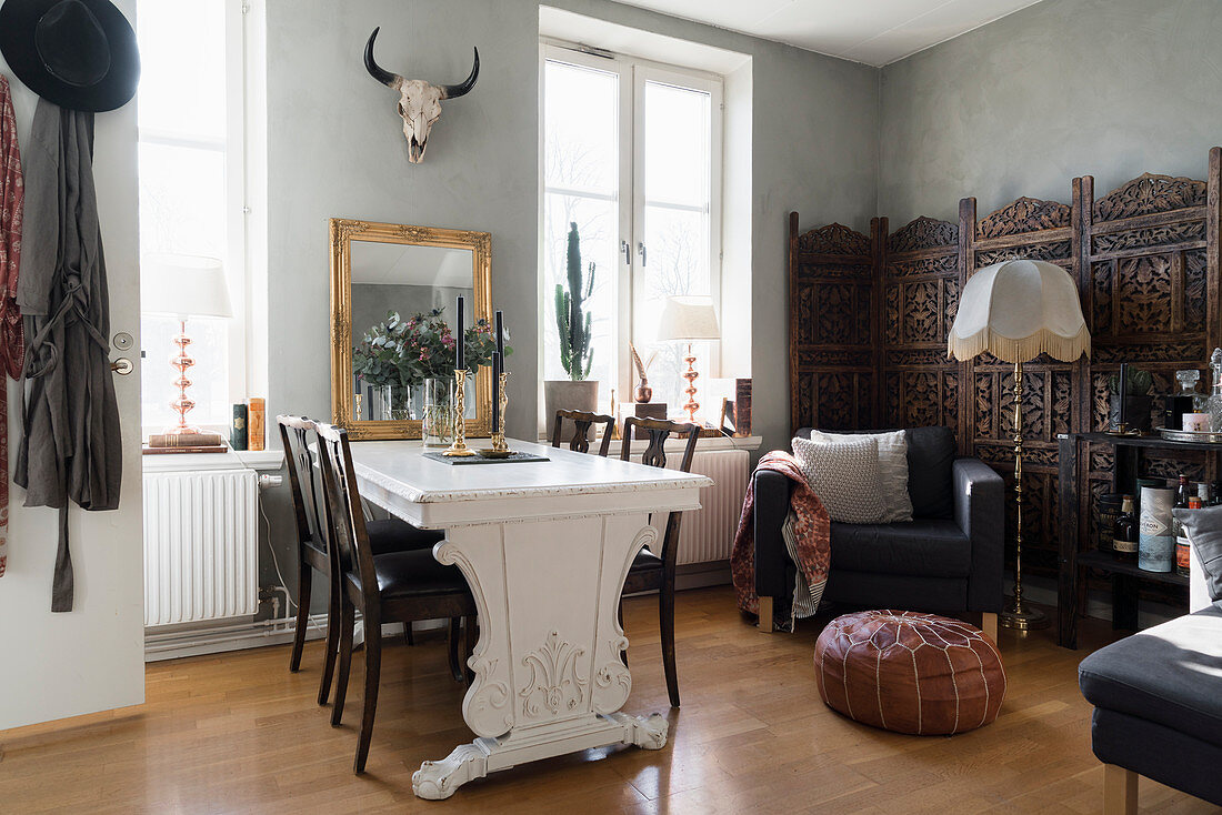Esstisch mit Stühlen, Sessel und Paravent in offenem Wohnraum mit hellgrauer Wand
