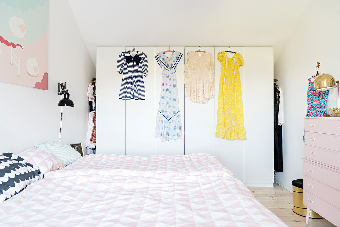 Bett und begehbarer Kleiderschrank mit aufgehängten Kleidern im Schlafzimmer