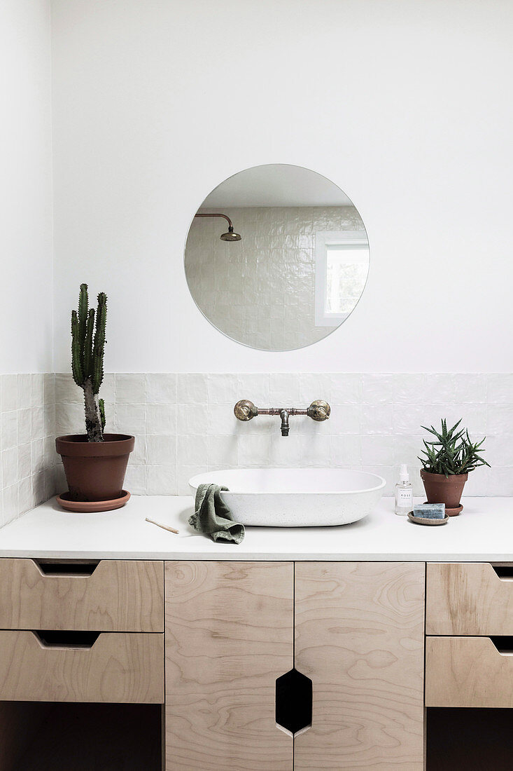 Runder Spiegel über dem Waschtisch mit hellen Holzfronten