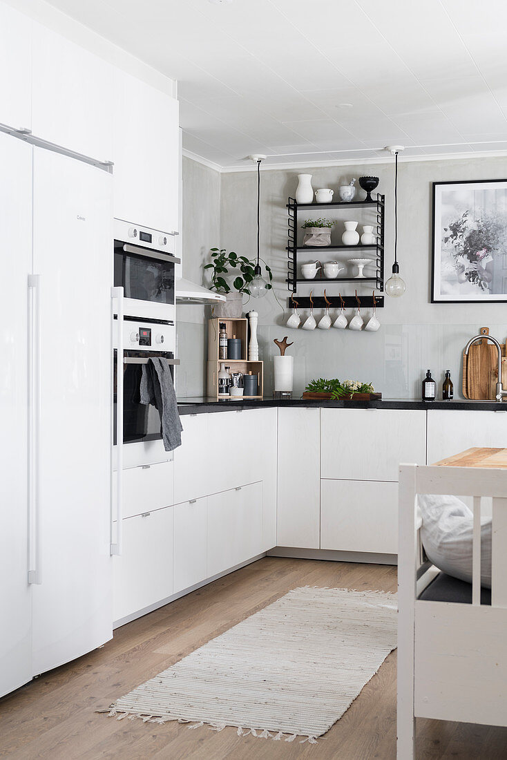 Weiße Küchenzeile mit schwarzer Arbeitsplatte und Einbaugeräten