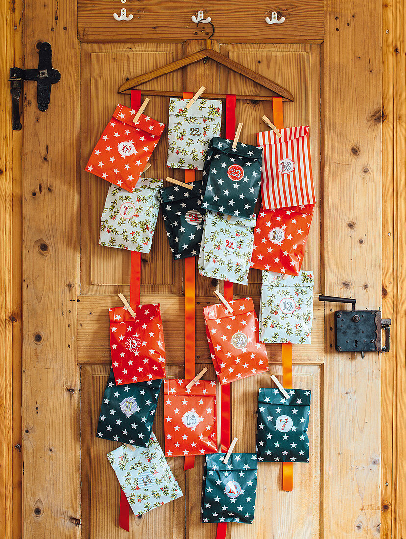 DIY Advent calendar made of colourful paper bag hanging on a wooden door