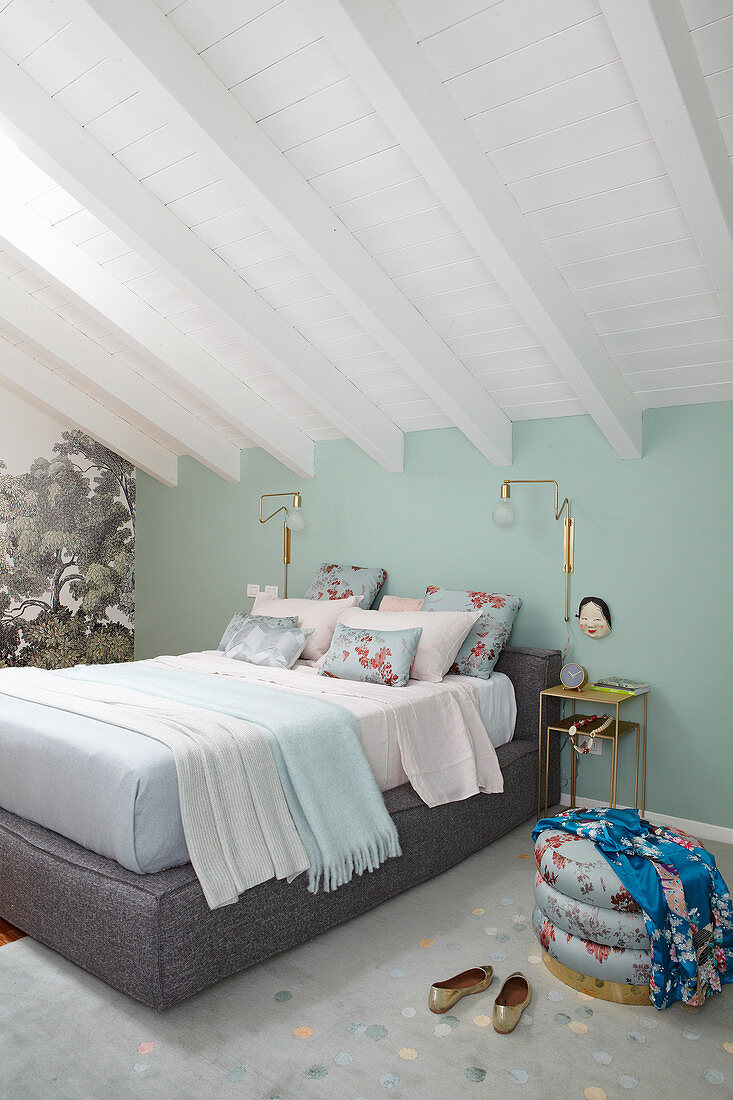 Doppelbett im Schlafzimmer mit mintfarbener Wand und weiß gestrichener Holzdecke