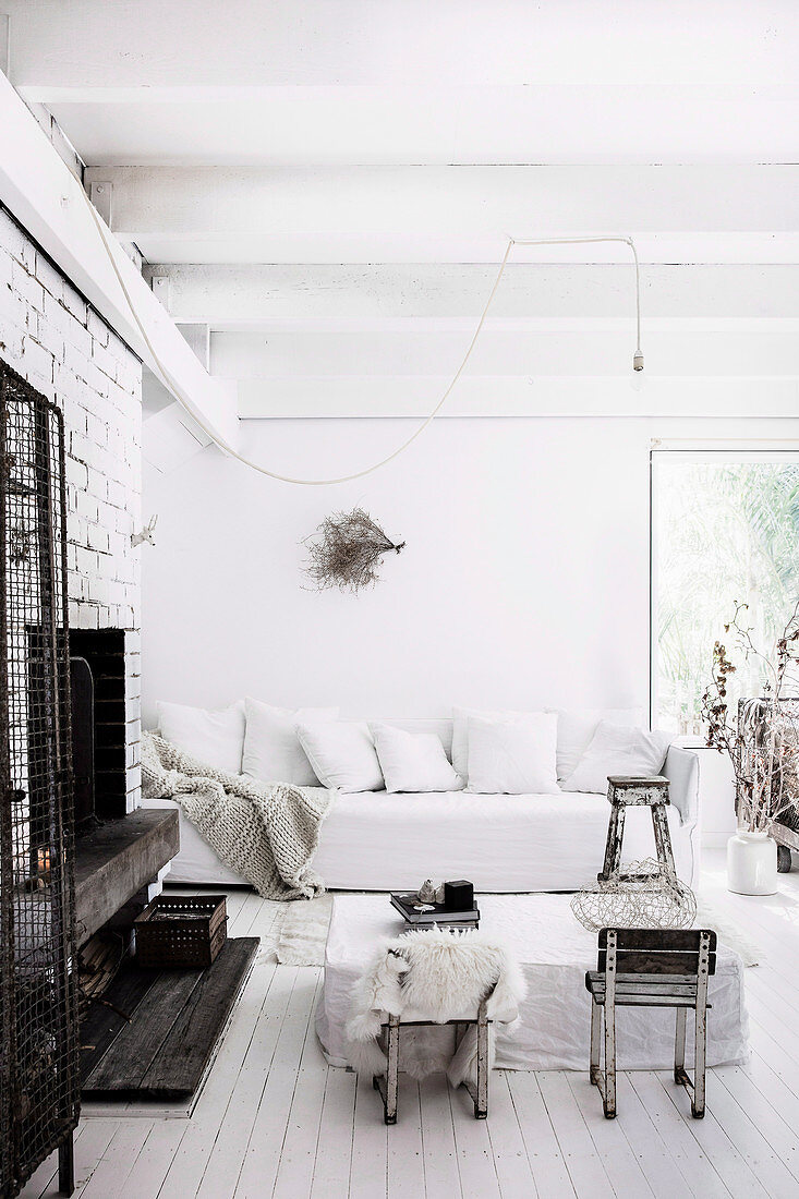 Wohnzimmer in Weiß mit Sofa und Vintage-Sitzmöbeln um Hussen-Coffeetable