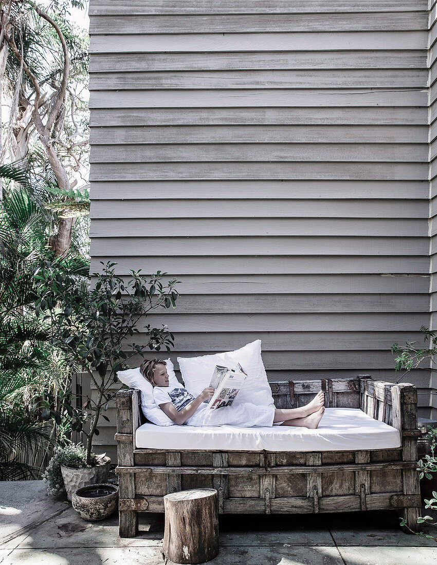 Imposantes Outdoor-Tagesbett aus Holz mit weißer Matrazenauflage auf Terrasse