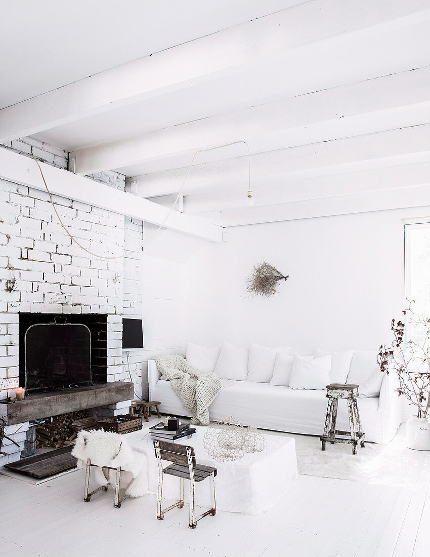 Wohnzimmer in Weiß mit Sofa und Vintage-Sitzmöbeln um Hussen-Coffeetable