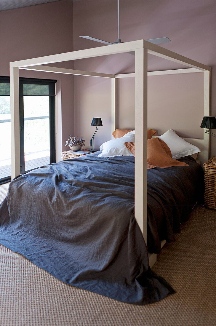 Himmelbett mit dunkelblauer Decke im Schlafzimmer mit braunen Wänden