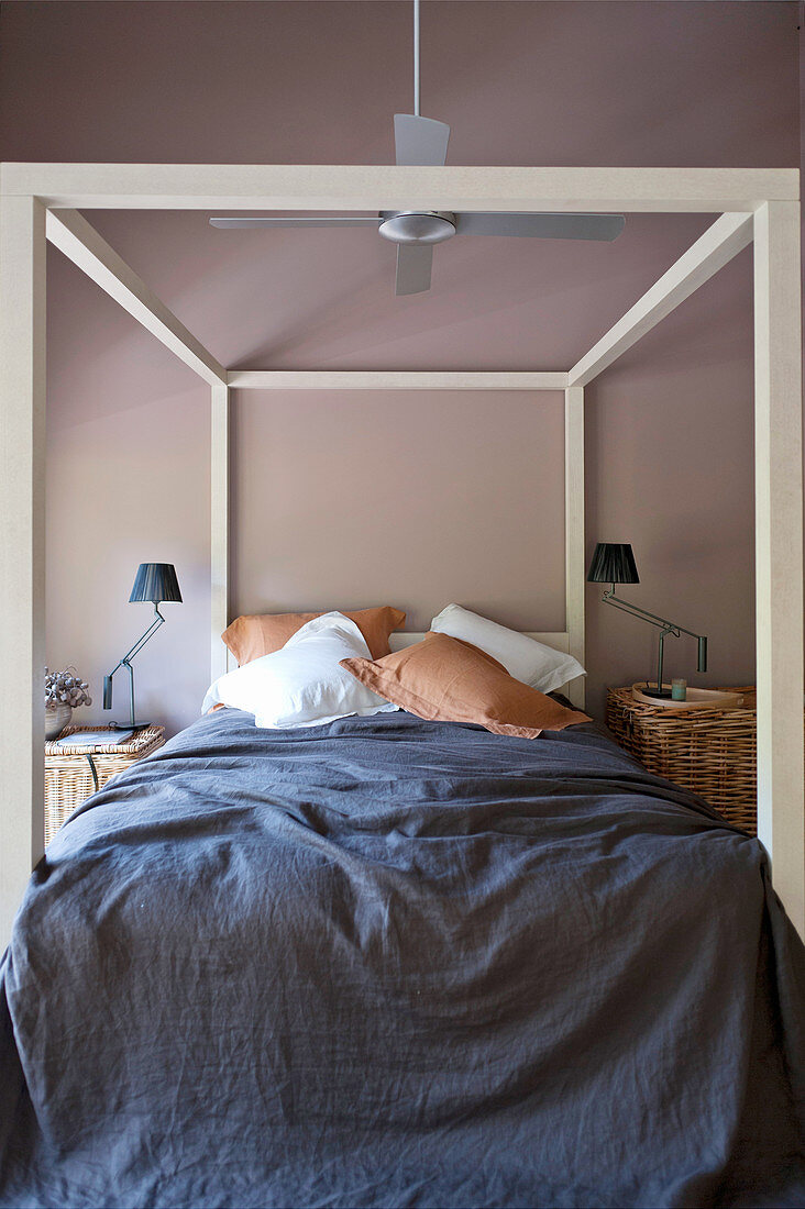 Himmelbett mit dunkelblauer Decke im Schlafzimmer mit brauner Wand