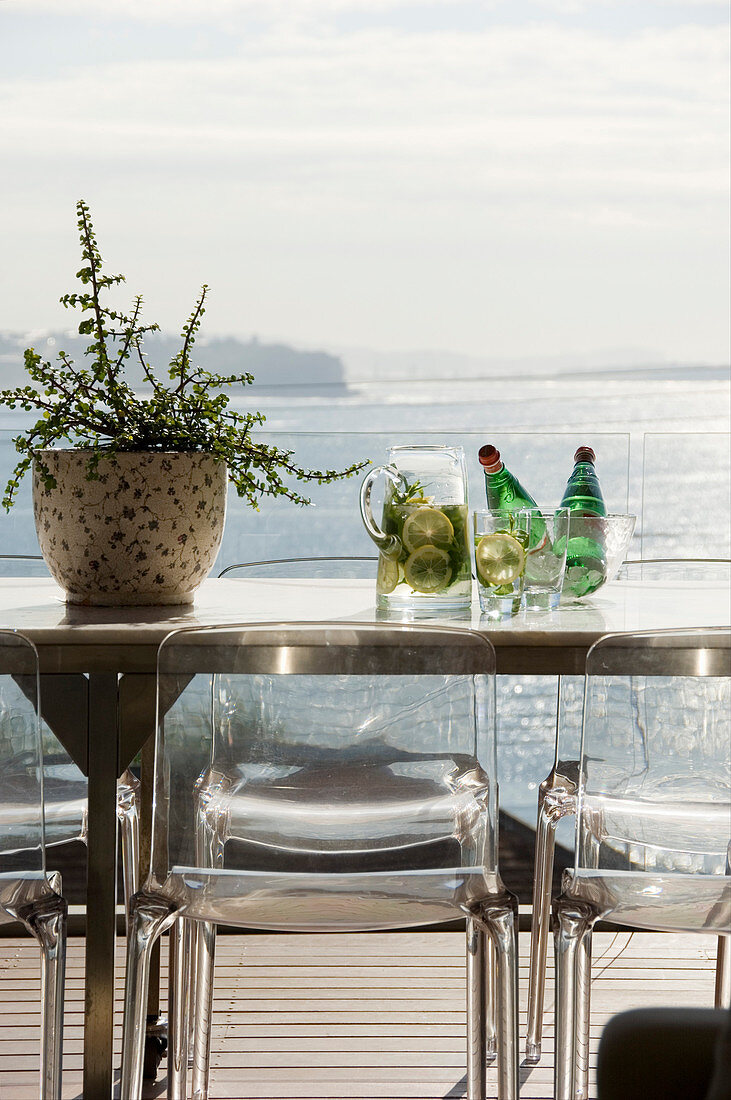 Klassikerstühle um Metalltisch auf Balkon mit Meerblick