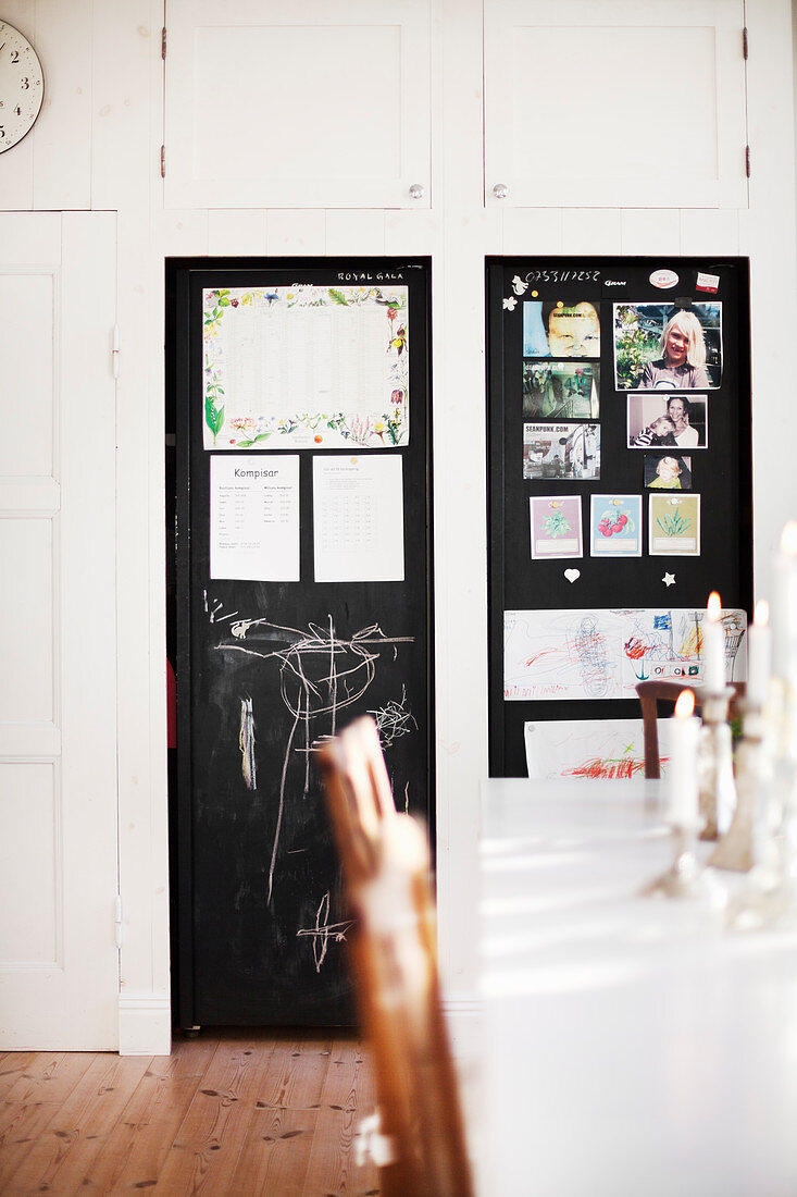 Blick über Esstisch auf schwarze Tür mit Tafellack und Pinnwand