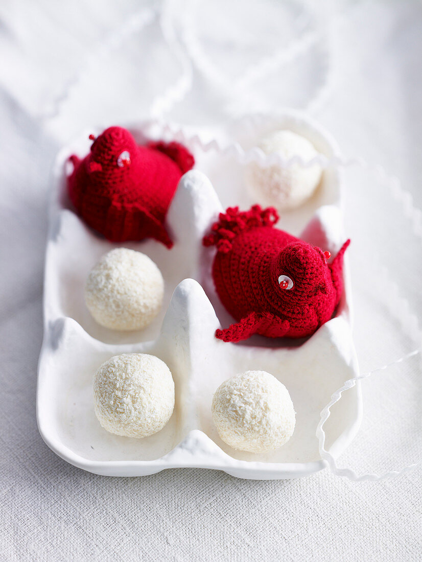 Crocheted red birds and truffle chocolates in a white egg box