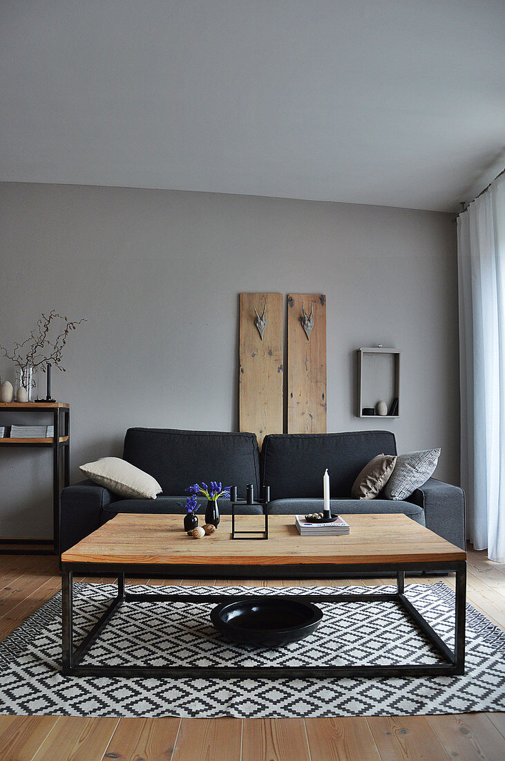 Wohnzimmer in Grautönen: Couch vor Wandpaneel und Couchtisch auf Teppich