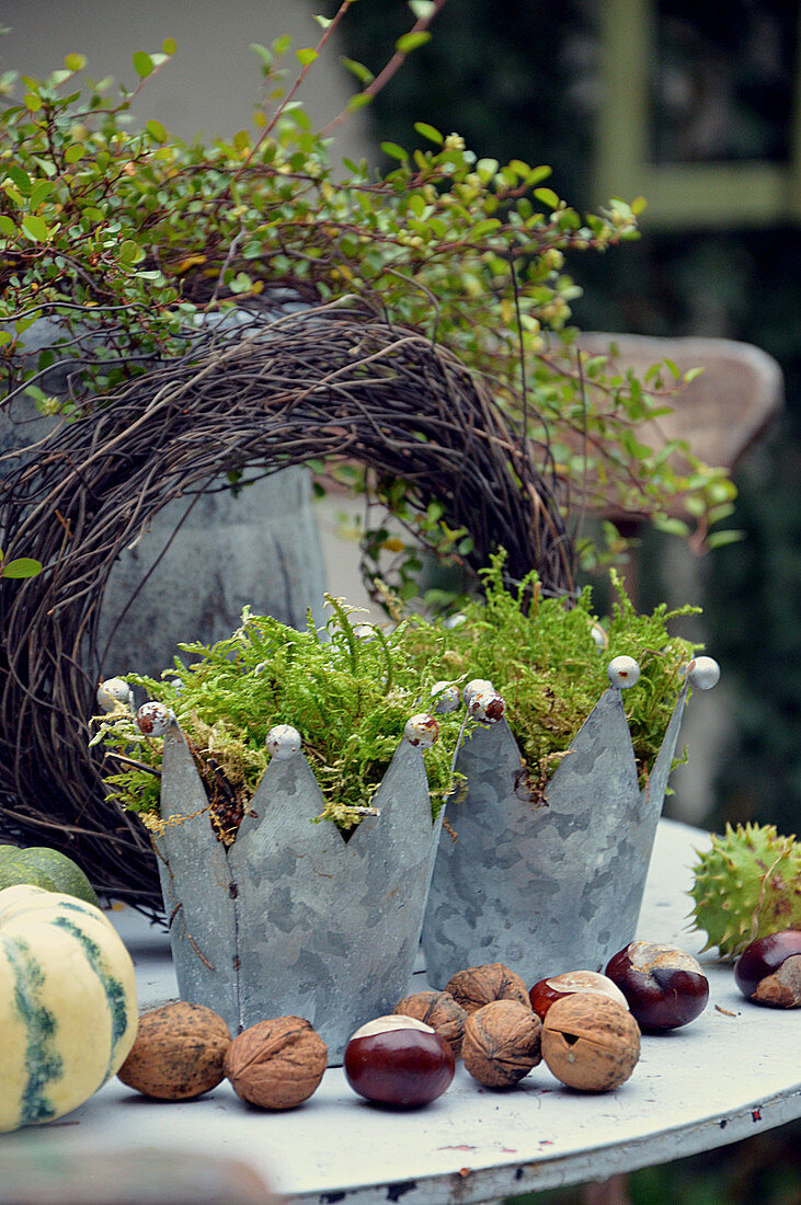 Zinkkronen mit Moos, Nüssen und Kastanien als Herbstdekoration