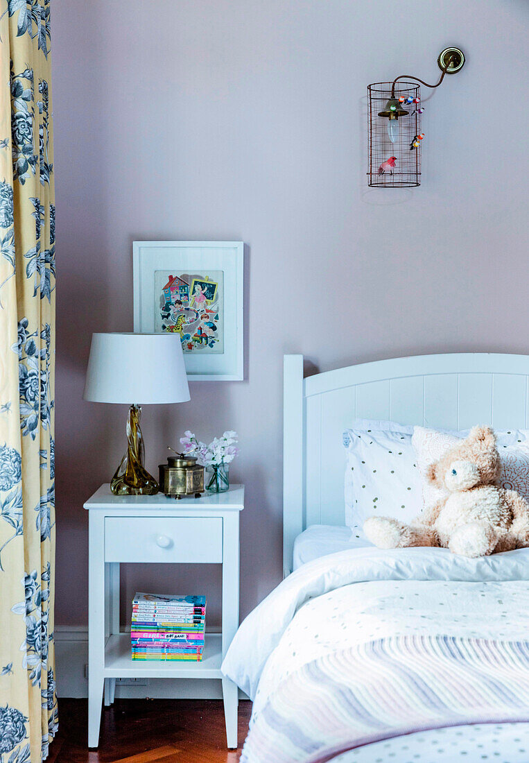 Bedside table and bed against pink wall in children's room