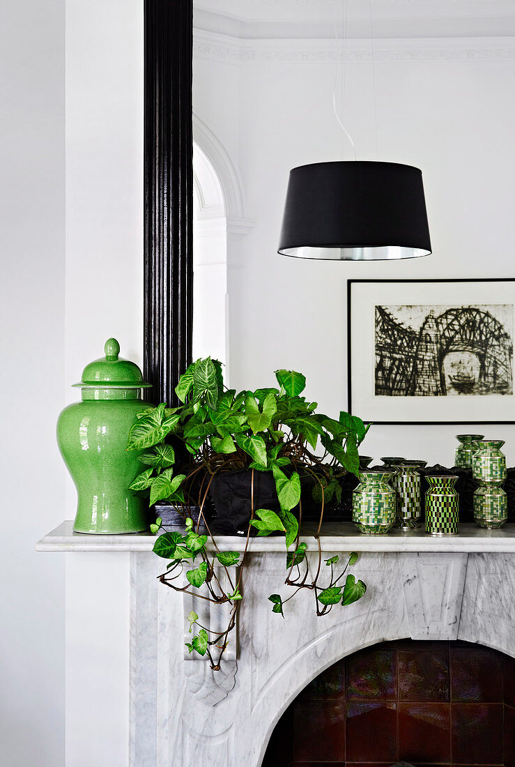 Green vases and houseplant on mantelpiece