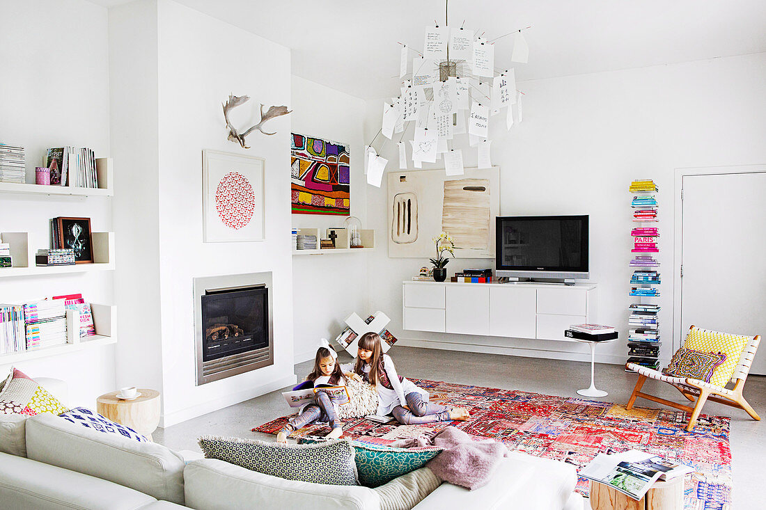 White living room with colorful accessories, reading girls on the carpet