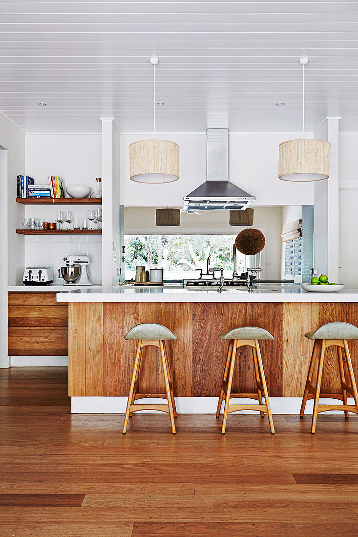 Bar stool on kitchen island with wooden front, white wooden ceiling in open kitchen