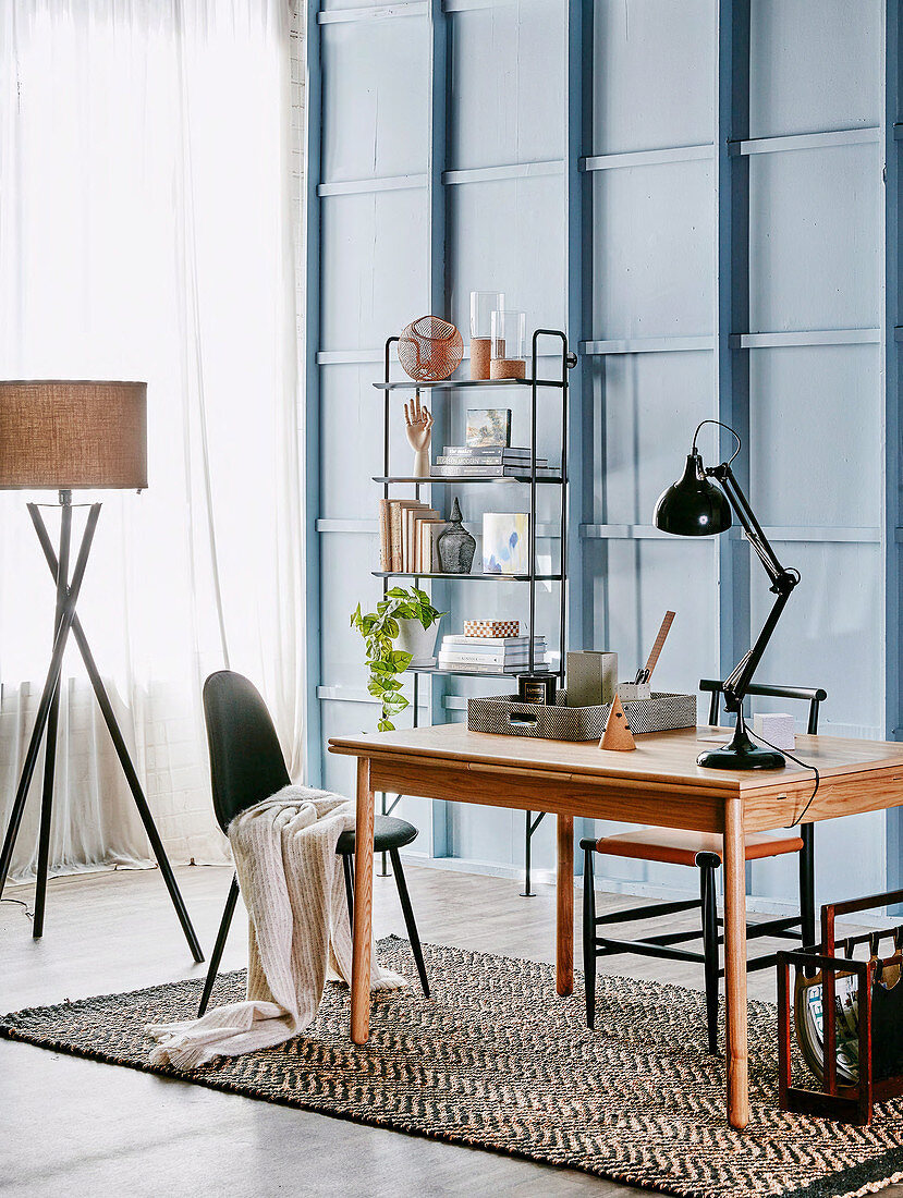 Wooden table with articulated lamp, open shelf and floor lamp in the study