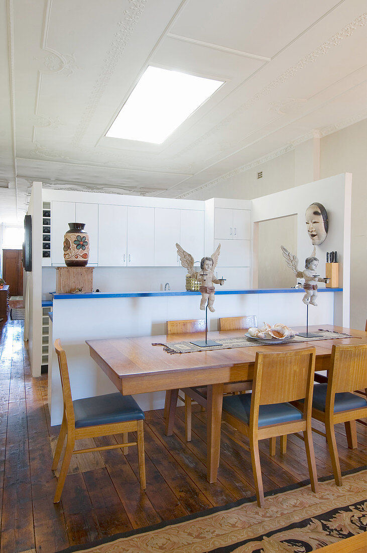 Stühle um Esstisch mit Putten vor Küchentheke und eingebauter Küche in offenem Wohnraum