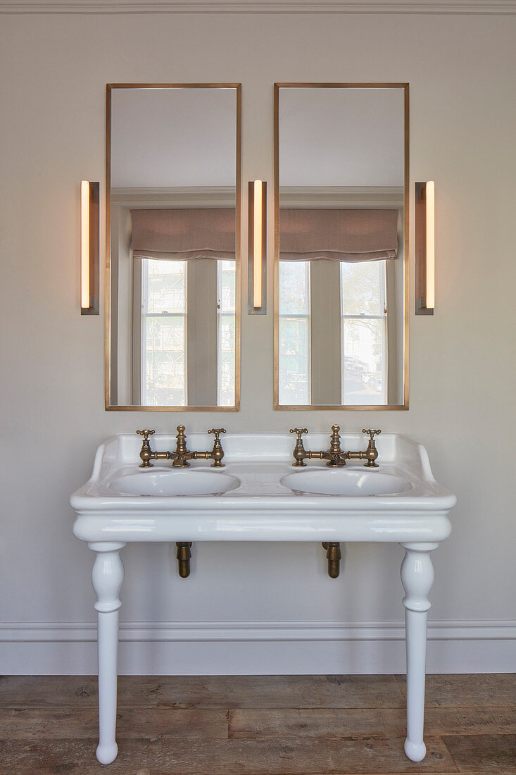 Vintage-style washstand with twin sinks, two mirrors and three wall lamps in bathroom