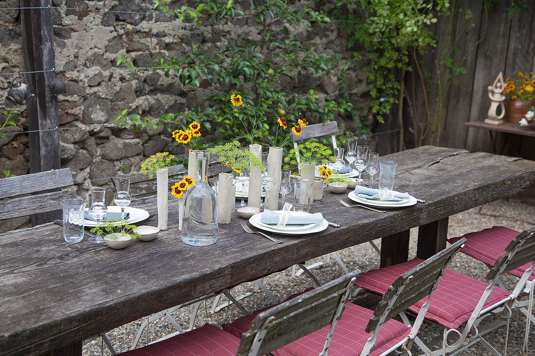 Rustikaler, gedeckter Tisch mit Blumendekoration auf der Terrasse