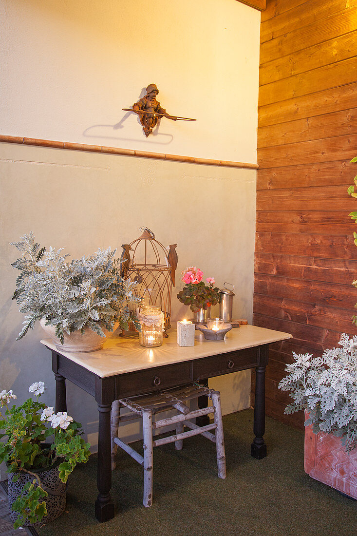Tisch mit Pflanze (Silberstaub), Windlichtern und Vogelkäfig
