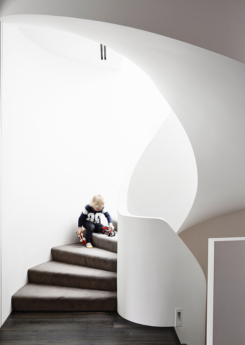 Junge spielt auf organisch geformter, gemauerter Treppe