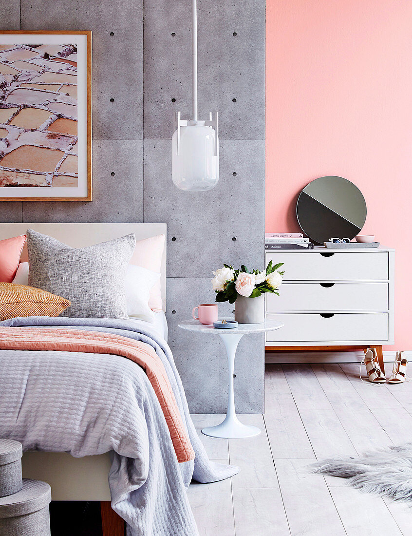 Bett an Raumteiler mit Beton-Tapete im pastellfarbenen Schlafzimmer