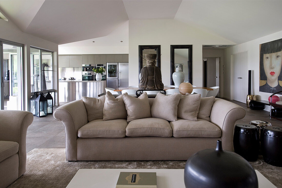 Beige sofa and exotic accessories in open-plan interior