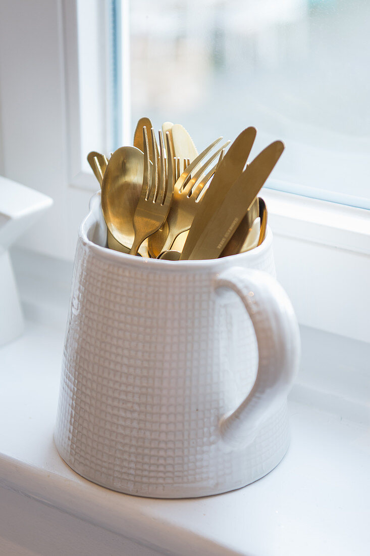Gold cutlery in jug with checked embossed pattern
