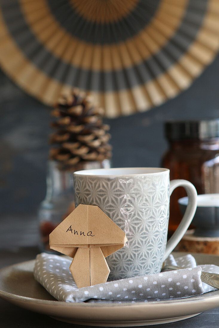 Aus Papier gefalteter Pilz als Namensschild an einer Tasse