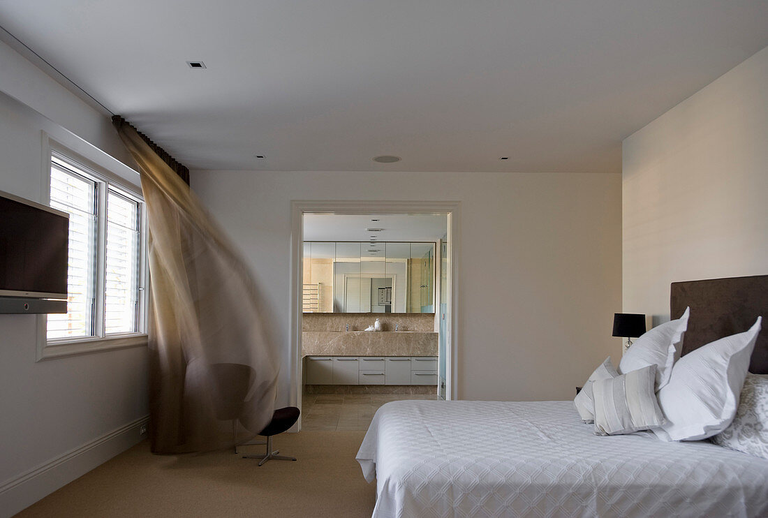 Double bed in minimalist bedroom with view into ensuite bathroom
