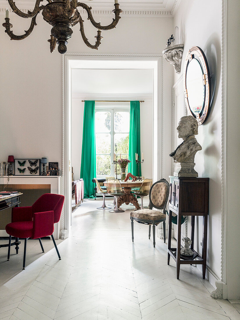 Büste auf Konsole unter Wandspiegel, roter Polsterstuhl im Vorzimmer