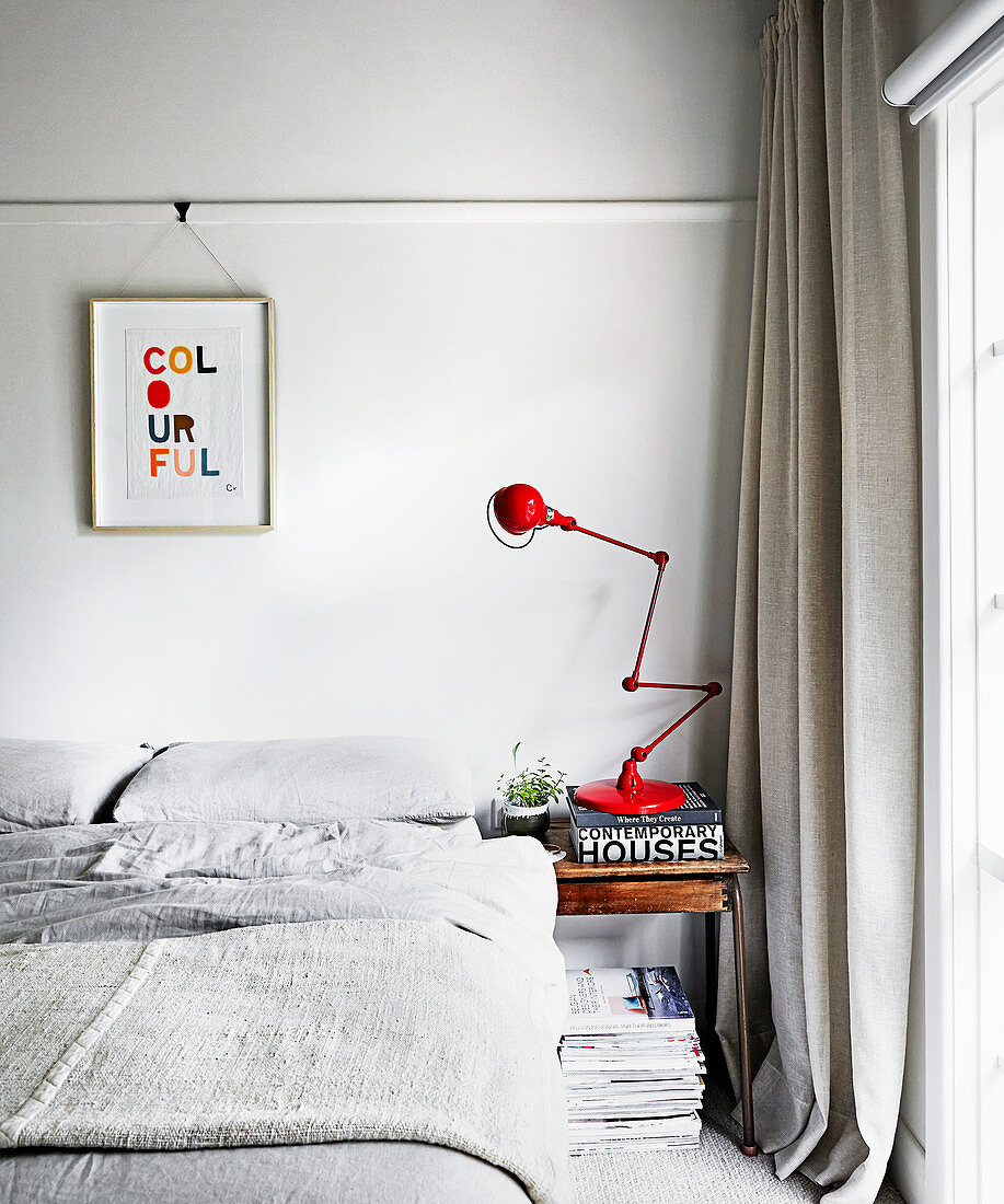 Red articulated lamp in the light gray bedroom