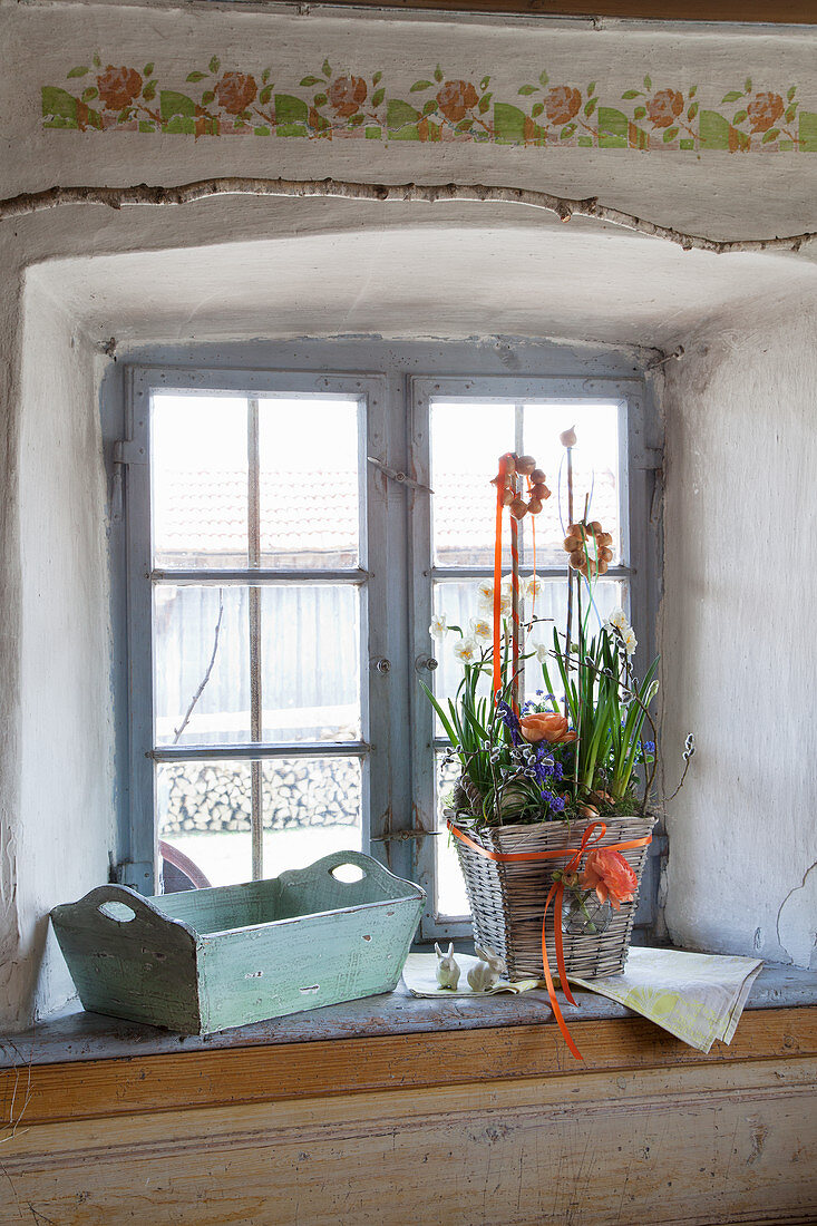 Easter arrangement in basket on sill of rustic window