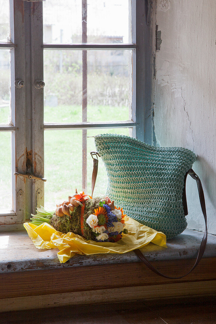Häkeltasche und ein Blumenstrauß im ländlichen Fenster