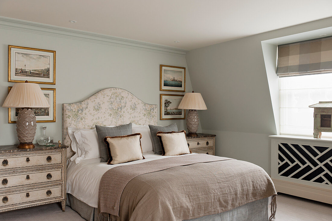 Elegantes Schlafzimmer in Erdtönen mit Doppelbett, flankiert von zwei Kommoden mit Lampen