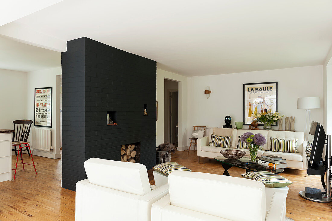 Lounge mit Fernseher und schwarz gestrichenem Ziegelkamin in offenem Wohnraum