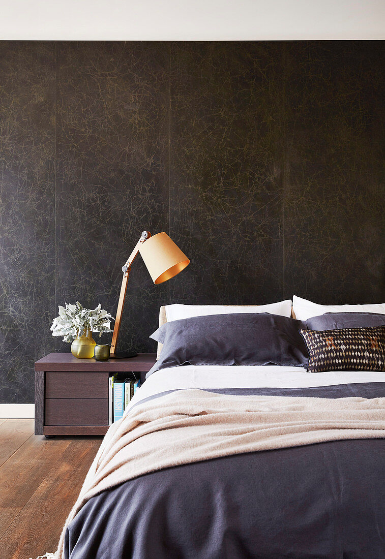 Schwarz marmorierte Wand hinter dem Bett im Schlafzimmer