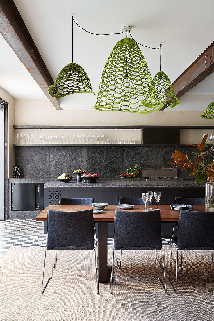 Green designer lights above the dining table in front of the open kitchen