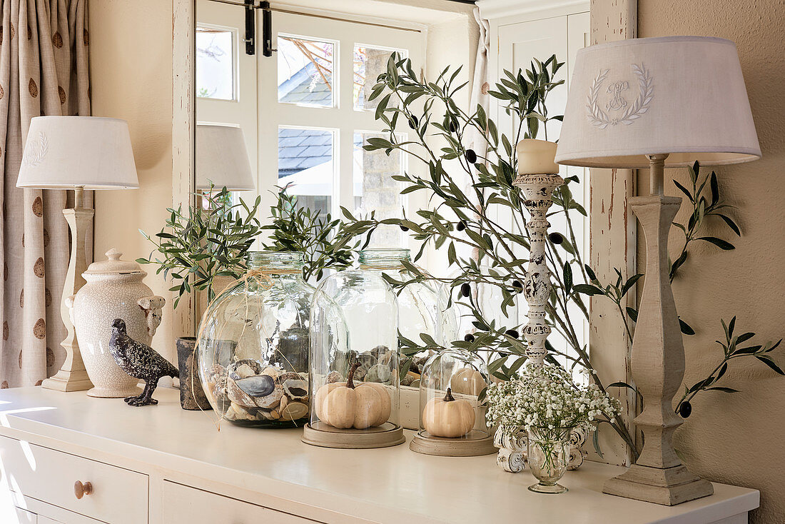 Table lamps, olive branches and glass vessels on sideboard