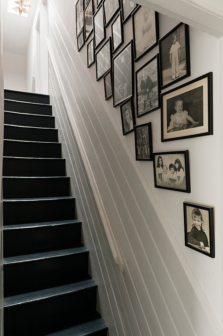 Gerahmte schwarz-weiße Familienfotos an der Wand entlang der Treppe