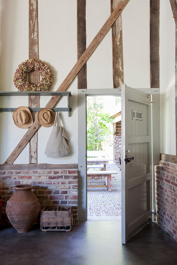 Open front door in converted barn with brick wall base
