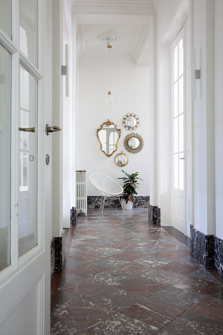 Collection of mirrors in hallway with chequered marble floor