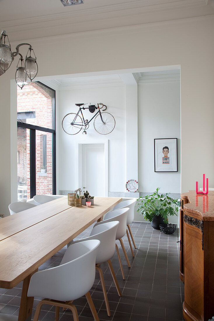 Shell chairs at wooden table in dining room with bicycle hung on wall