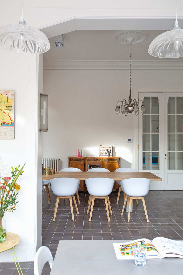 Shell chairs at wooden table in dining room of period building with stucco ceiling