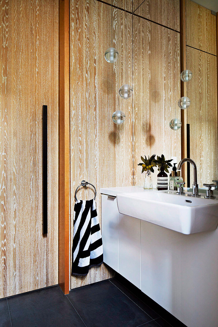 Waschtisch und Wandpsiegel im Badezimmer mit Holzverkleidung