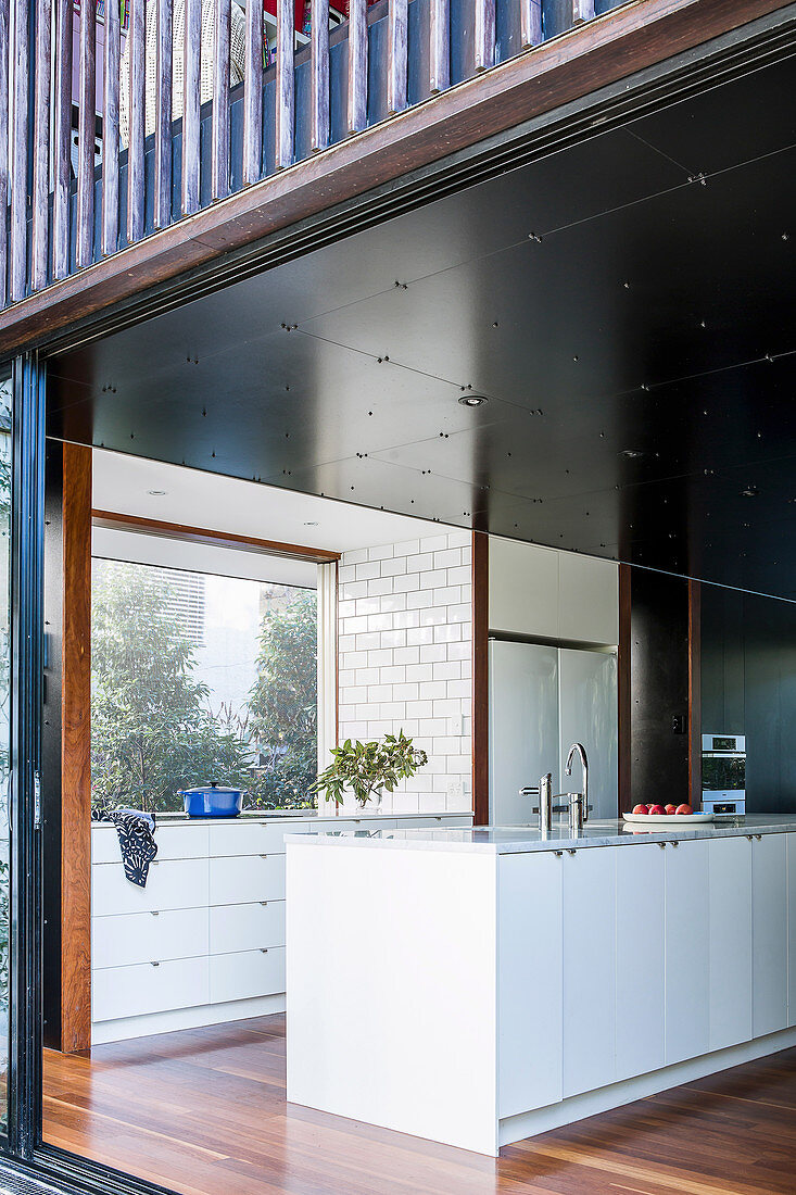 View through an open patio door into the modern, minimalist kitchen