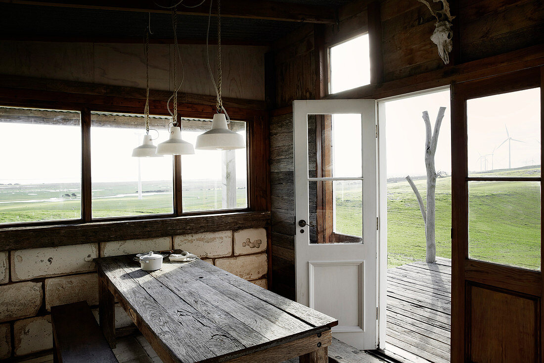 Holztisch mit Bank in rustikaler Hütte mit Kalksteinmauer