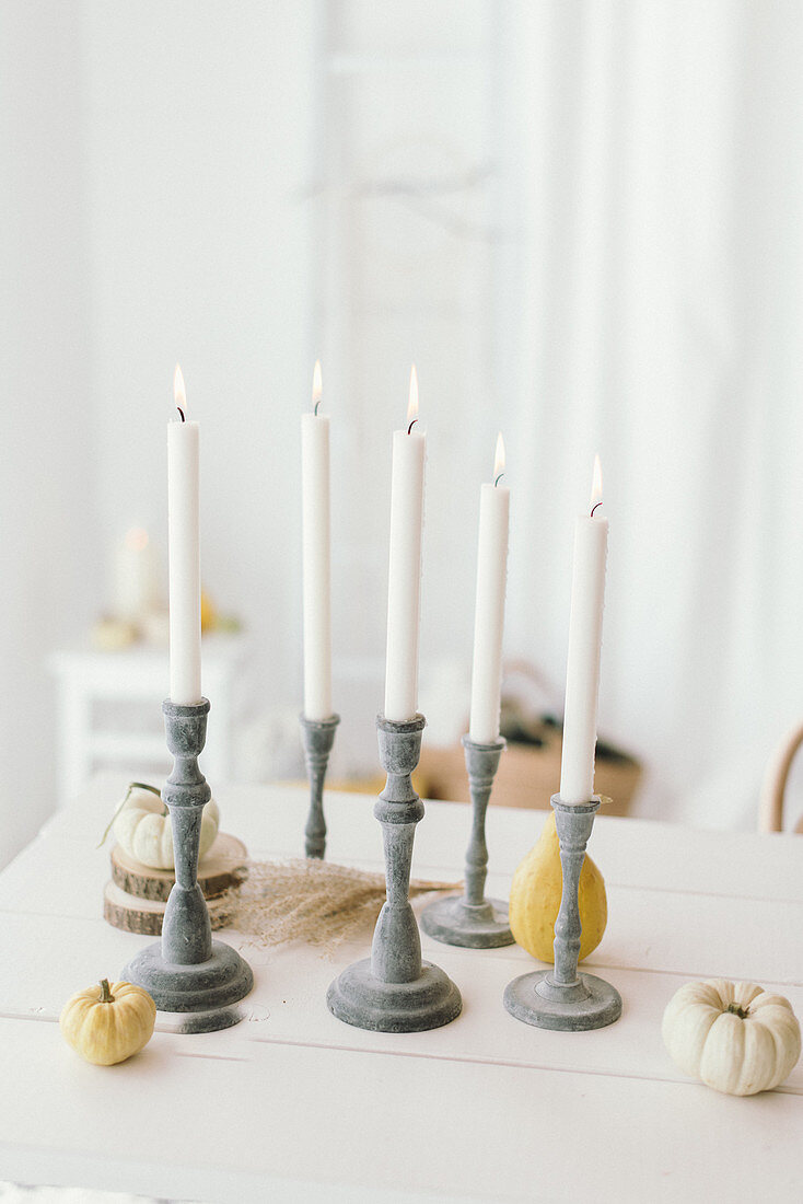 Autumnal arrangement of candlesticks, pumpkins and wooden discs on table