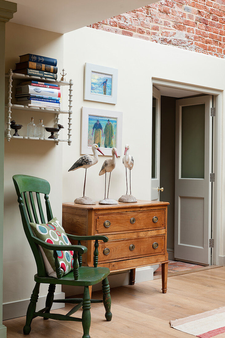 A green slat back chair in room corner with wooden chest of drawers